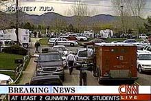 A crowd of emergency vehicles and reporter vans cluster outside of Columbine High School