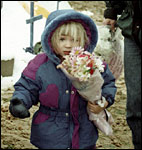 A little girl carries flowers to add to the memorials
