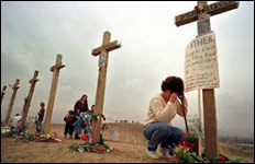 A woman cries at the foot of Dylan's cross